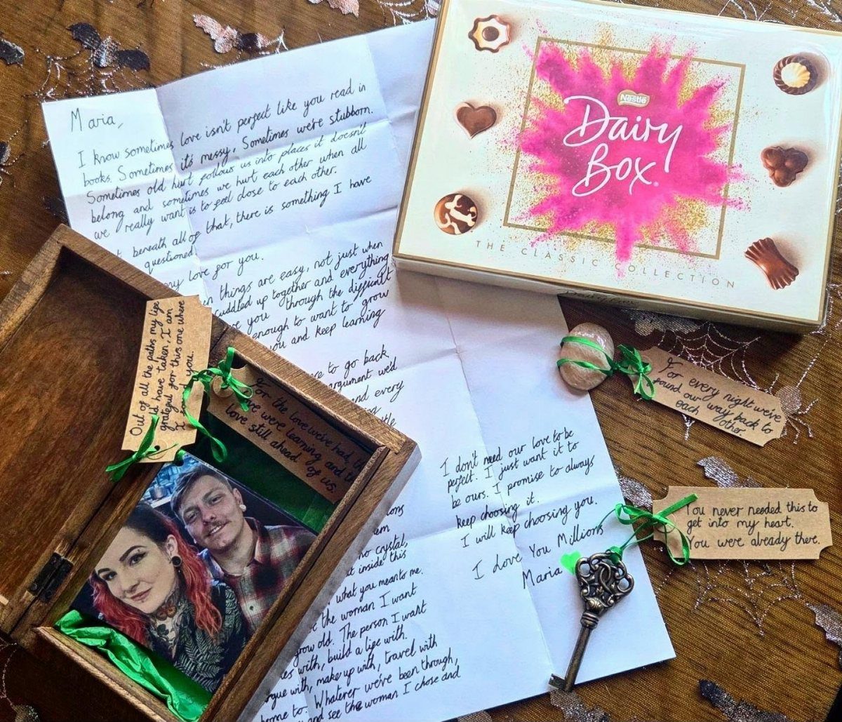 Wooden keepsake box with handwritten letters, couple's photo, and a box of chocolates.