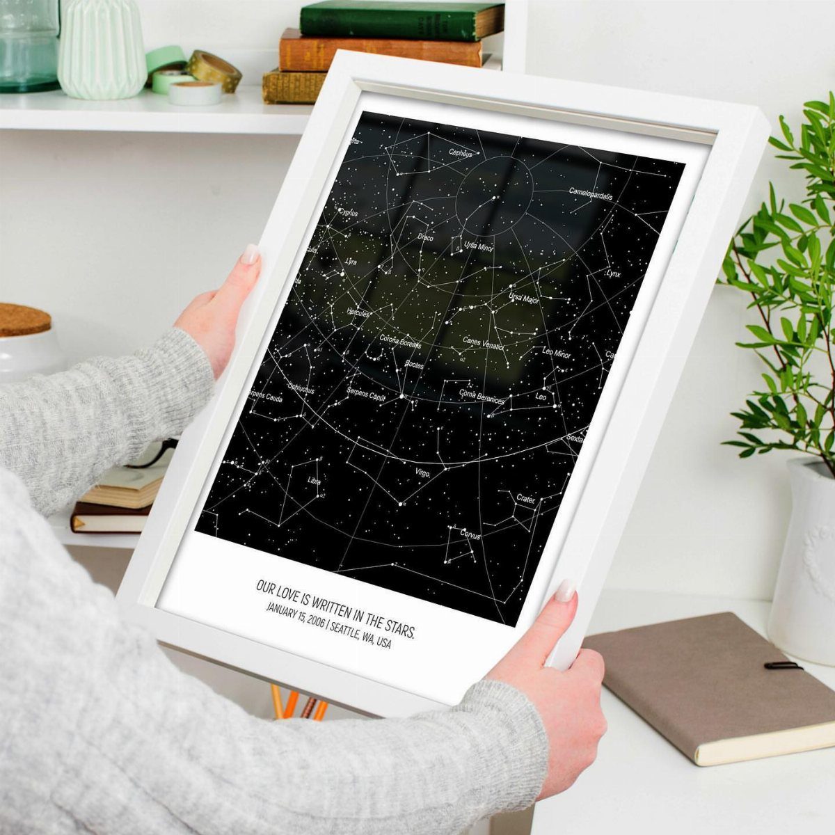 Framed custom star map showing a constellation night sky held by a person.