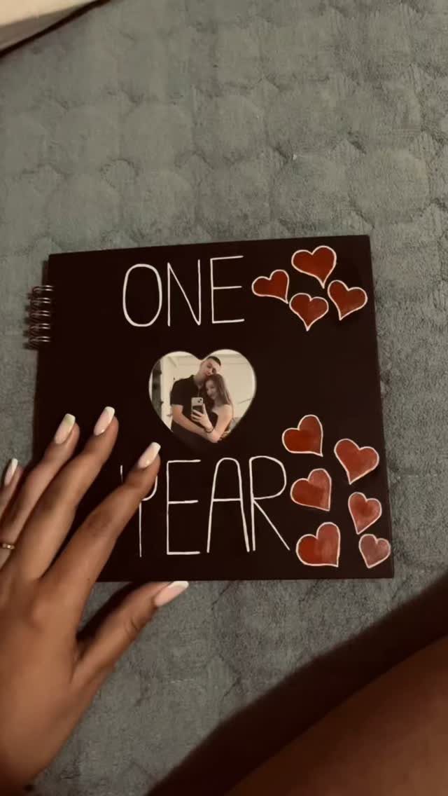Black spiral photo album with 'ONE YEAR' text and heart-shaped couple photo.