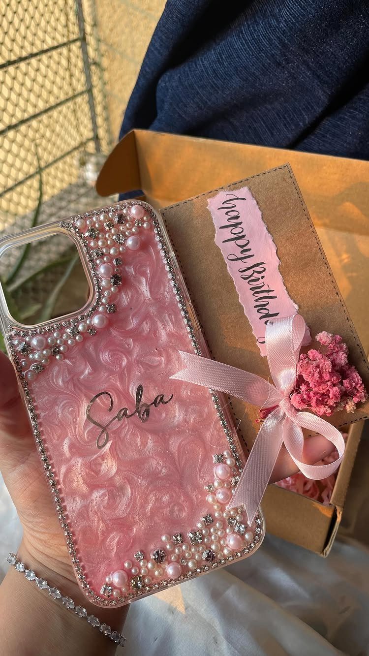 Pink textured phone case with pearls and crystals next to a birthday gift box