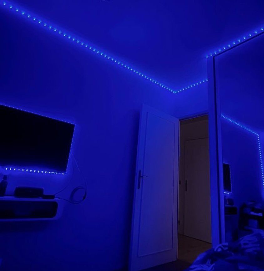 Blue LED strip lights illuminating the ceiling and walls of a modern bedroom