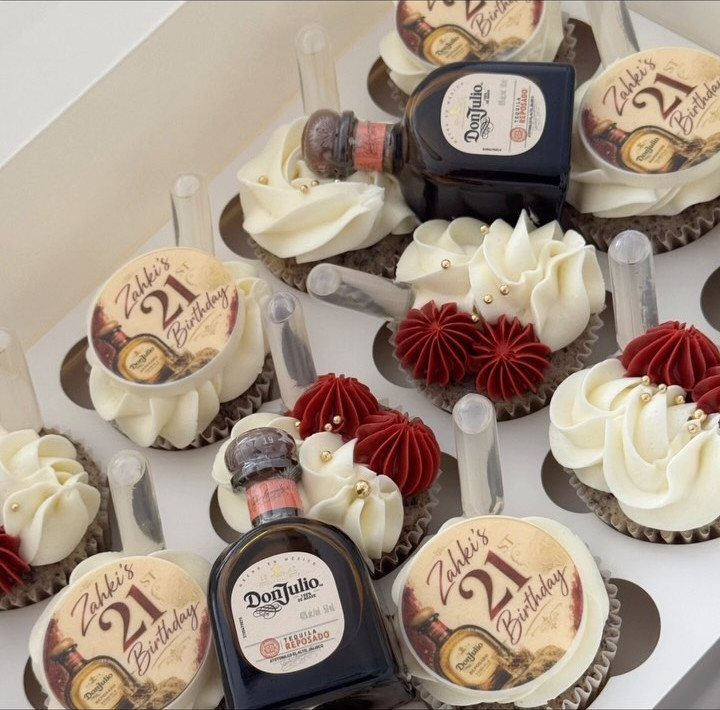 Cupcakes with miniature tequila bottles and 21st birthday toppers in a white box.