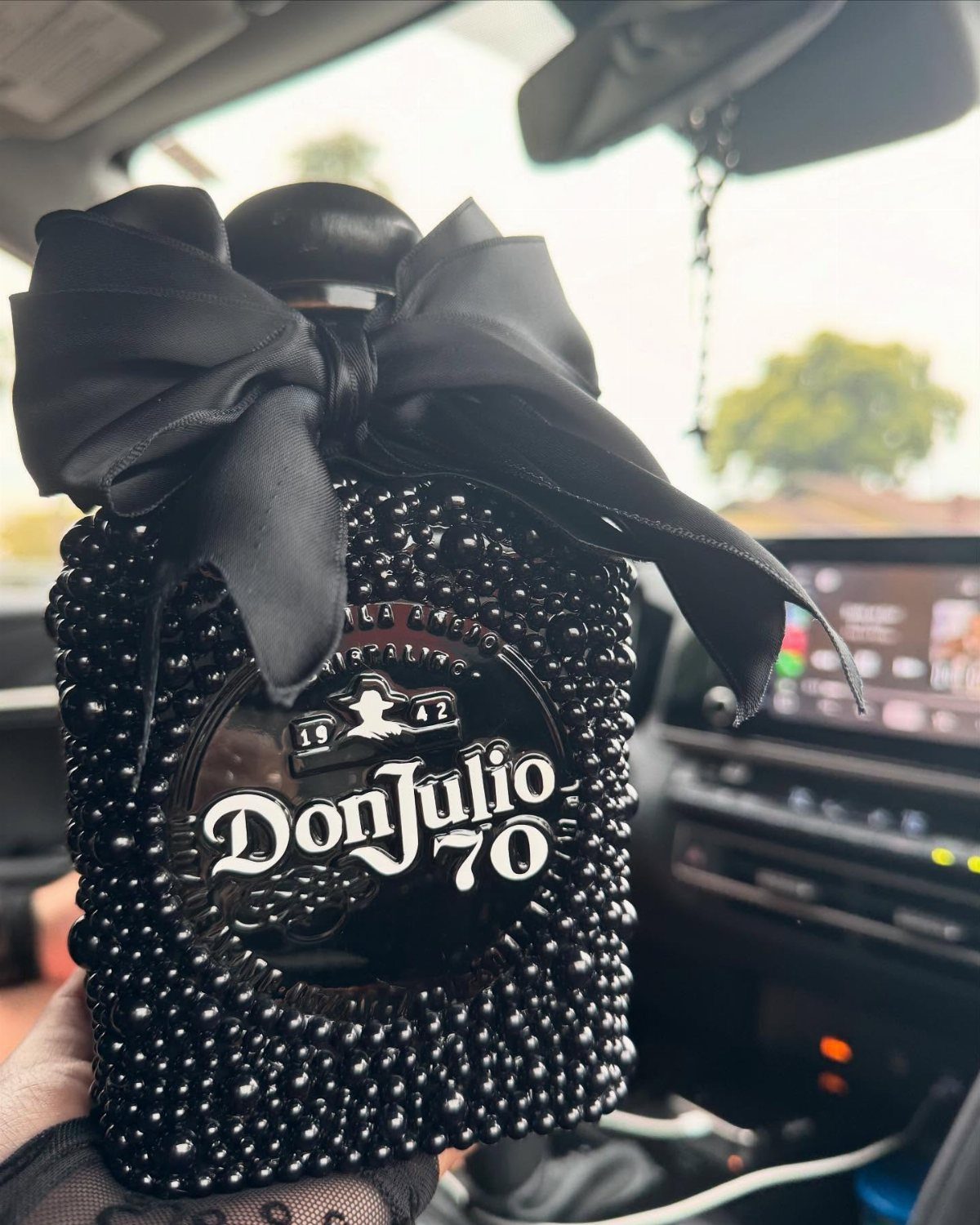 Don Julio 70 tequila bottle decorated with black beads and a satin bow.