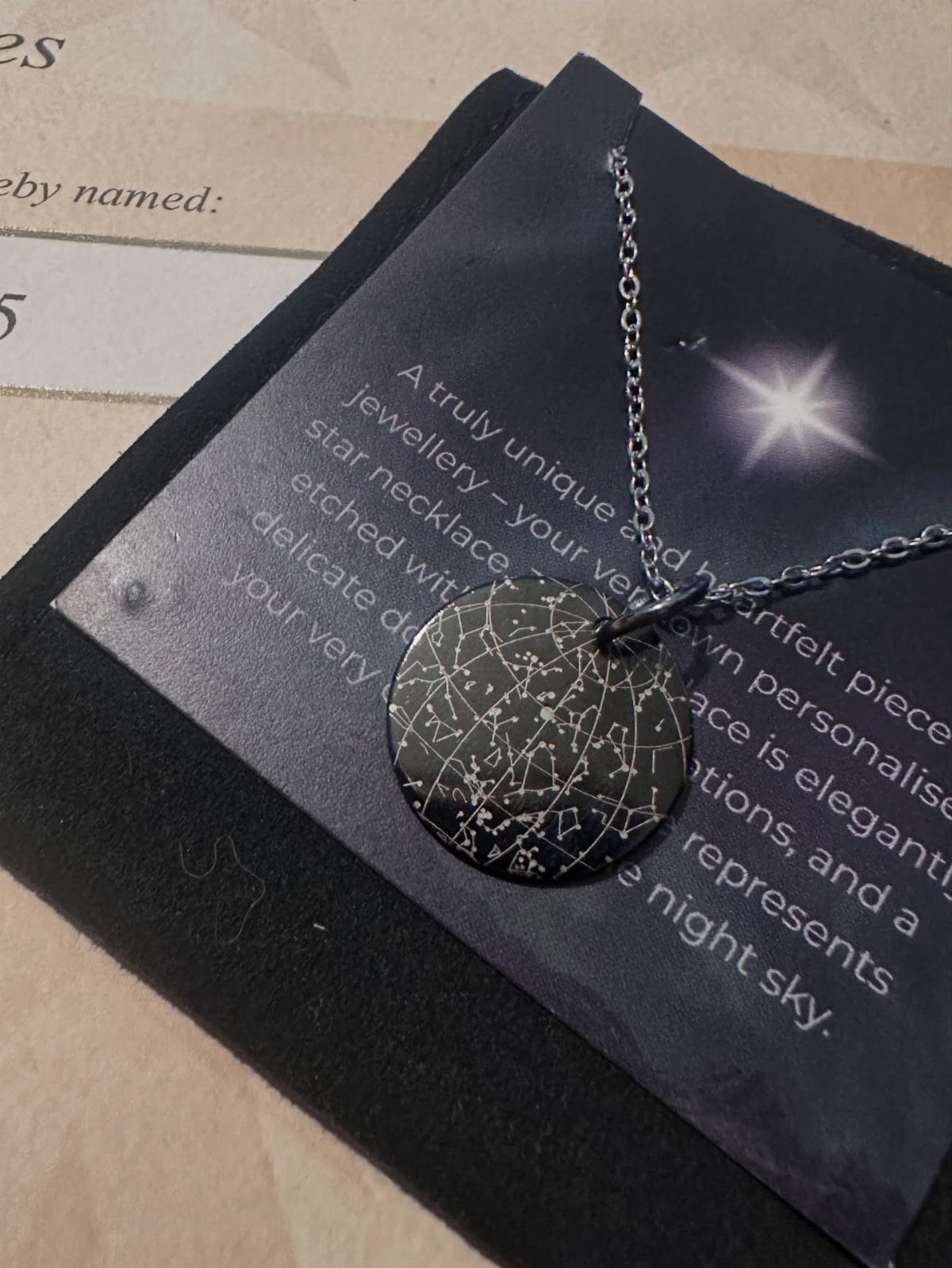 Silver star map necklace resting on a black descriptive gift card.