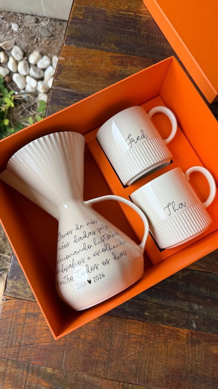 White ceramic coffee carafe and two personalized mugs in an orange gift box.