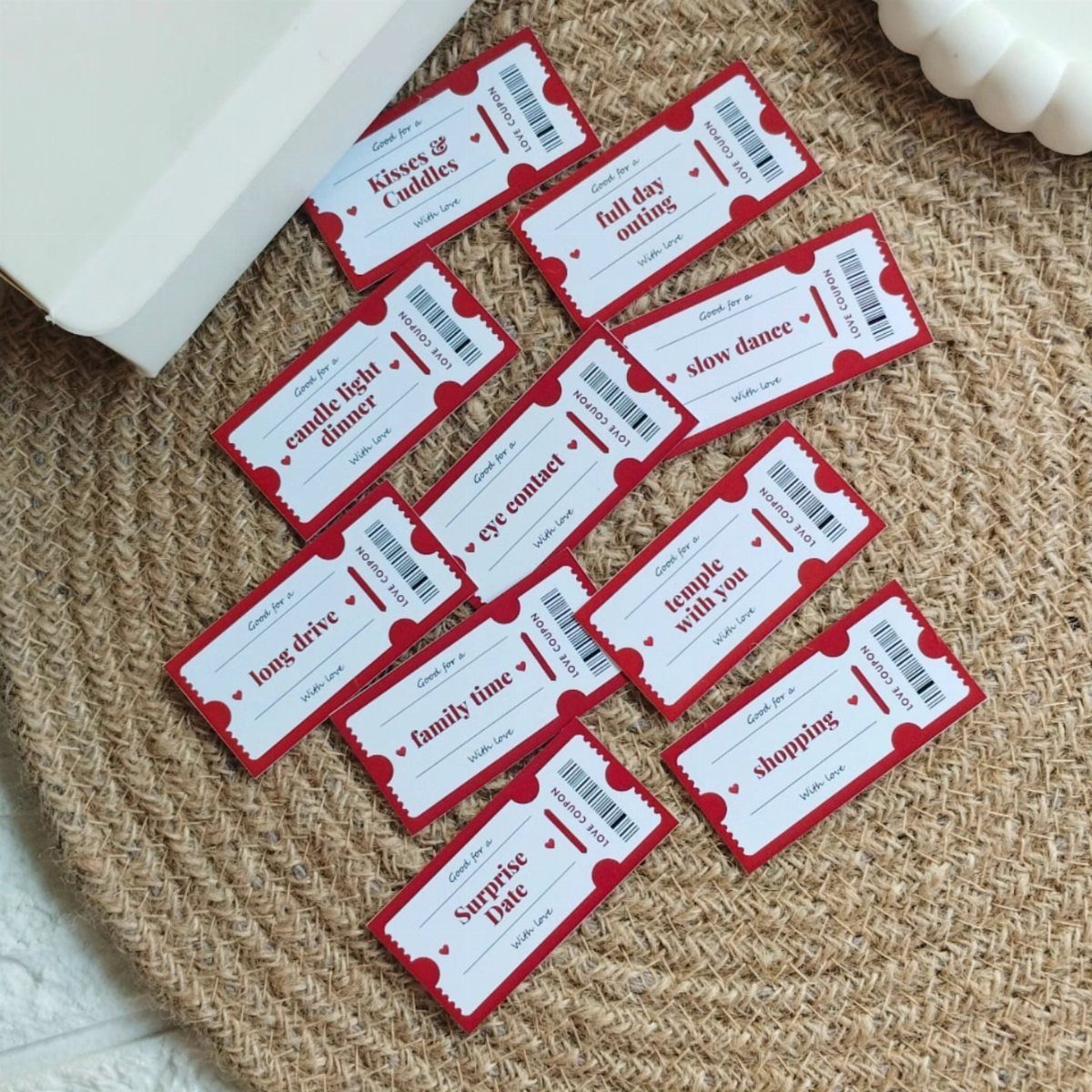 Handmade red and white love coupons scattered on a woven straw mat.