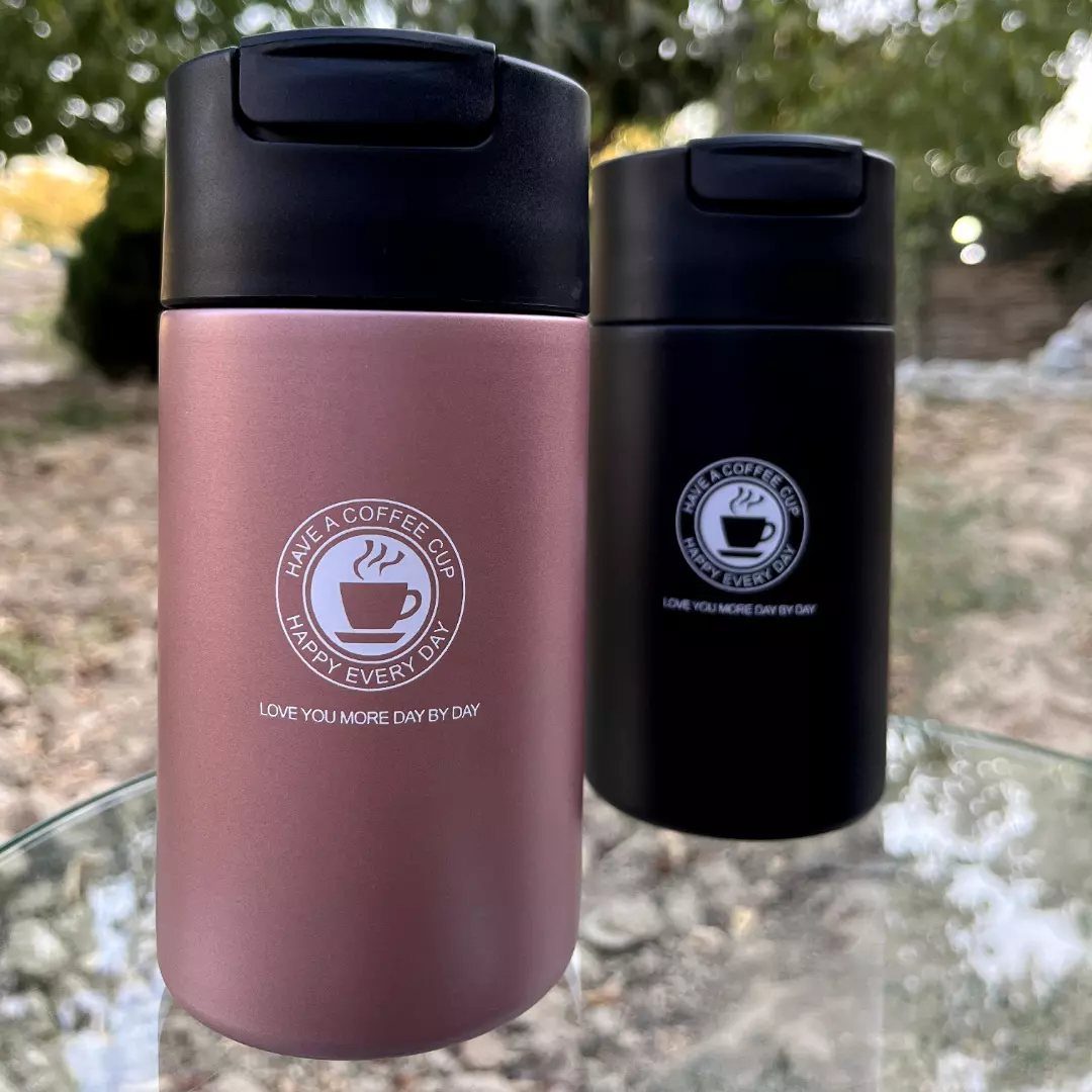 Two insulated travel mugs in rose gold and black with romantic coffee-themed text.