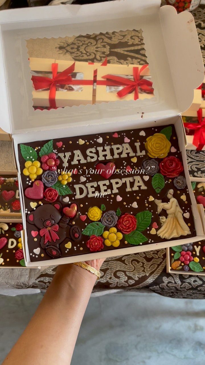 Decorated chocolate slab with names Yashpal and Deepta and colorful frosting flowers.