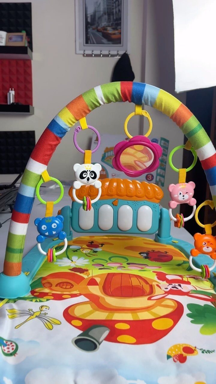 Colorful baby activity gym with hanging animal toys and a patterned play mat.