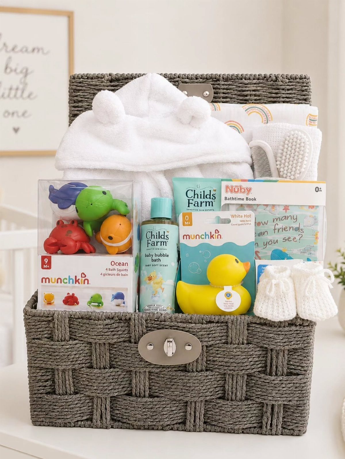 Baby bath gift basket with a rubber duck, colorful toys, and white towel.