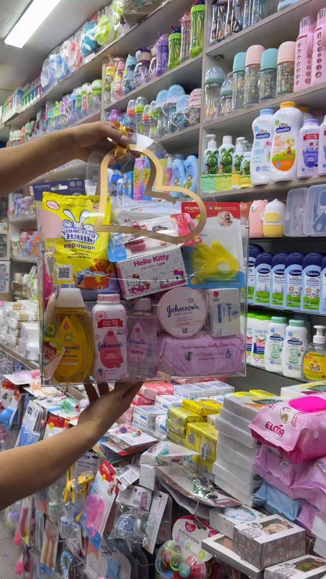Clear gift basket filled with baby lotions and powders held in a store.