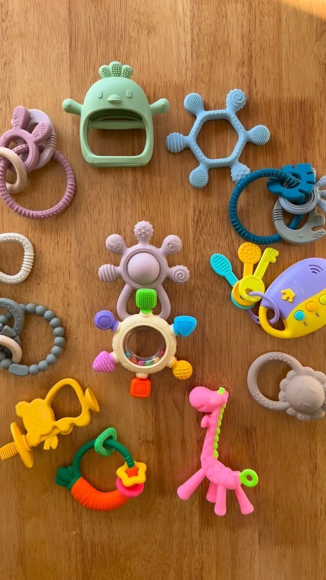 Colorful silicone baby teething toys scattered on a light brown wooden table.