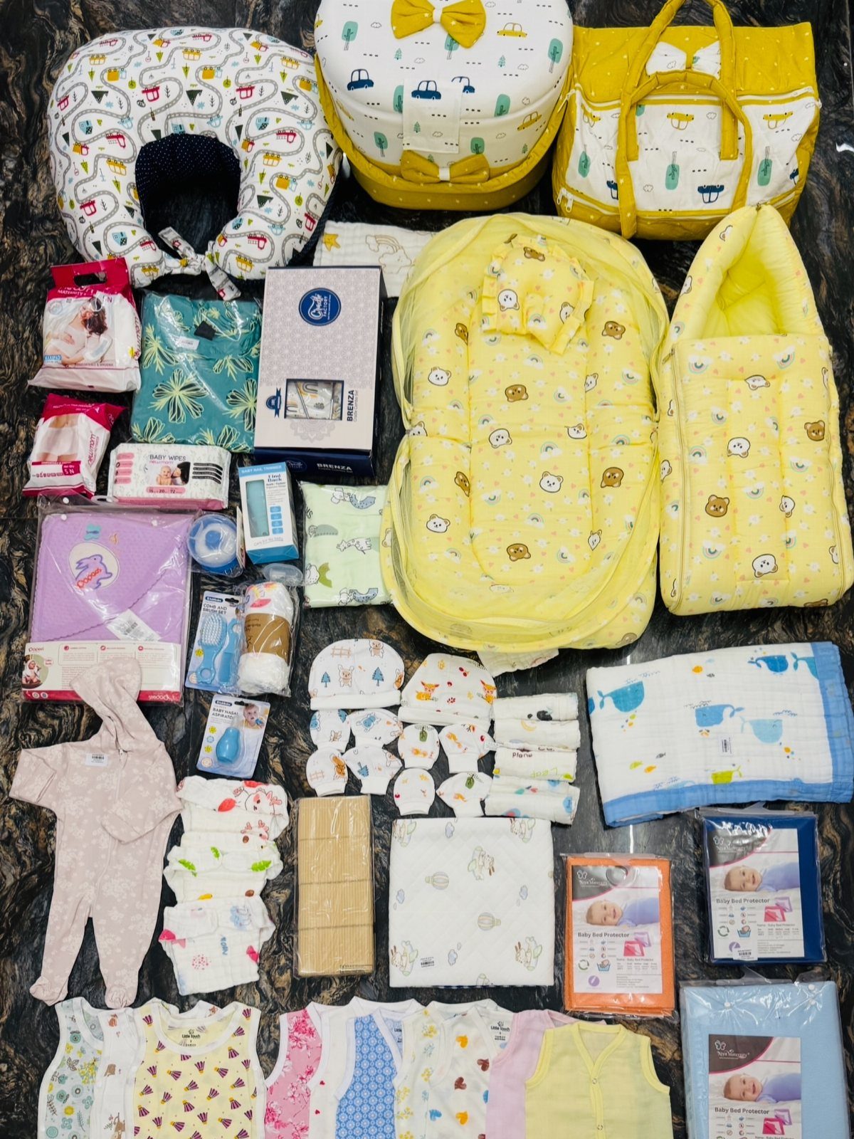 Assorted baby essentials including yellow bags, clothing, and toiletries arranged on a table.