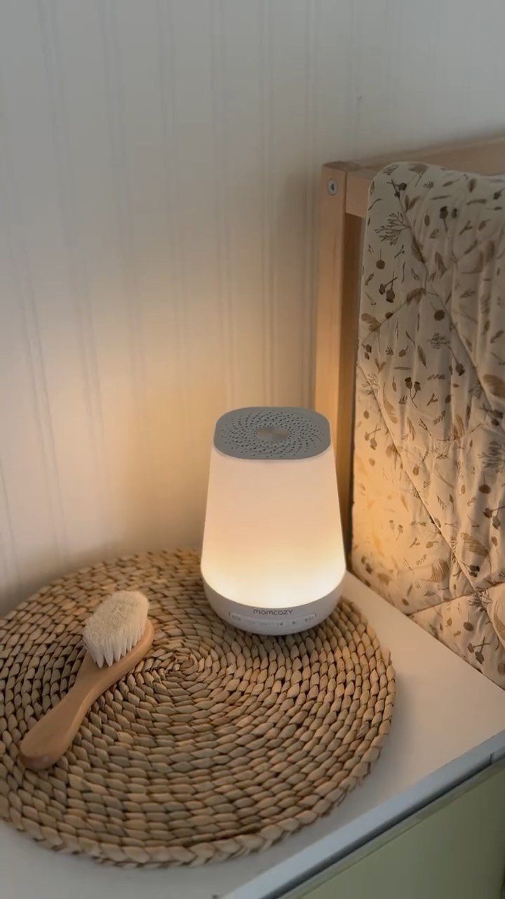 White glowing nightlight and wooden baby brush on a woven mat by a crib