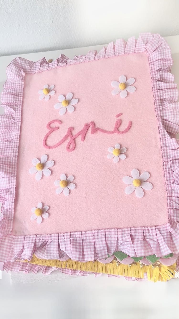 Pink baby blanket with white daisies and the name Esmé embroidered in cursive.