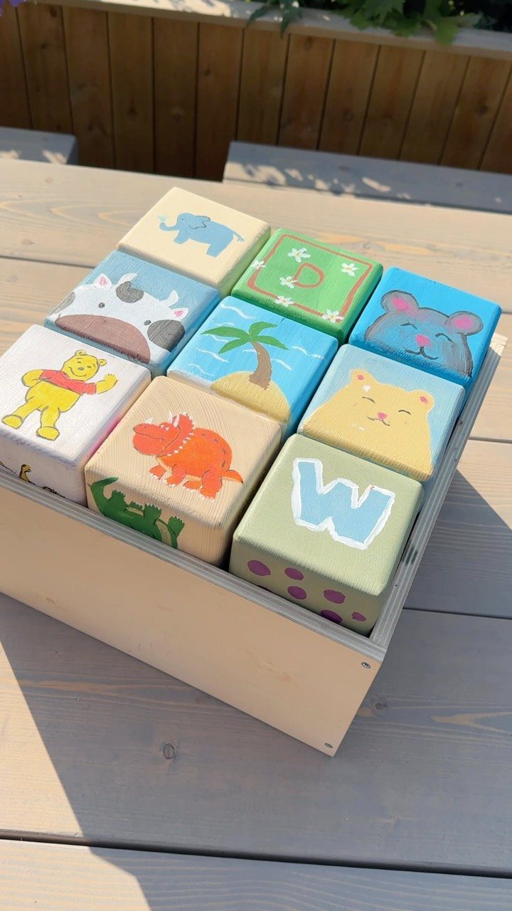 Painted wooden blocks with animals and letters inside a light wooden box.