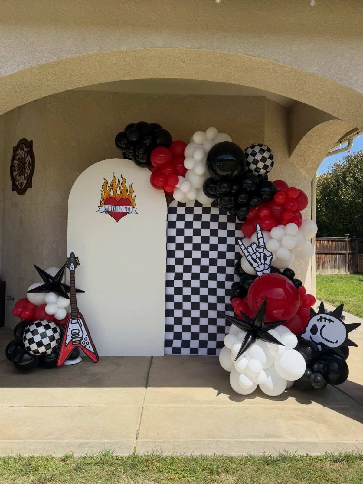 Rock and roll party setup with red, black, and white balloons and electric guitar.