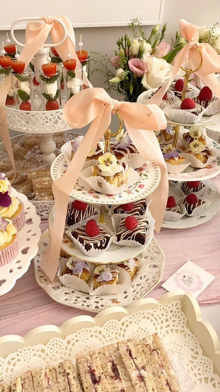 Tiered dessert stand with pink ribbons and assorted sweets at a tea party.