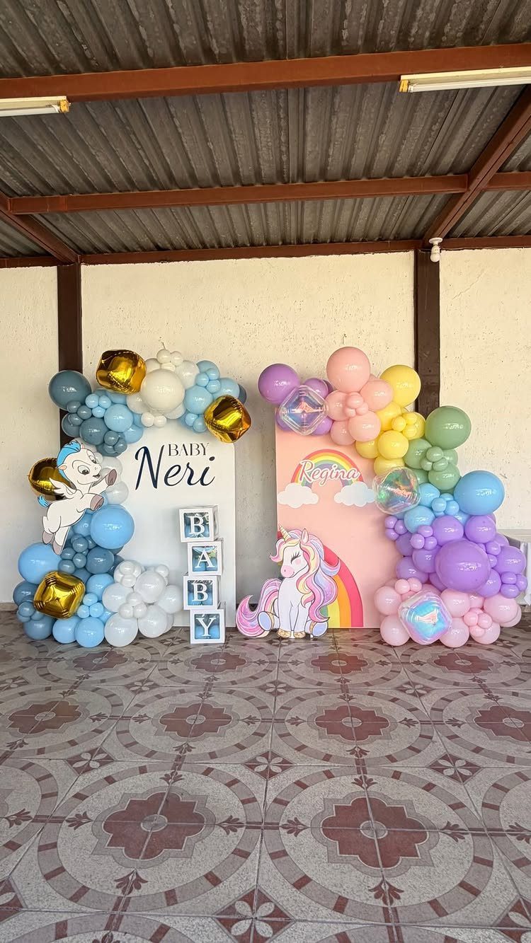 Balloon arches in blue and pastel colors with a unicorn and rainbow backdrop.