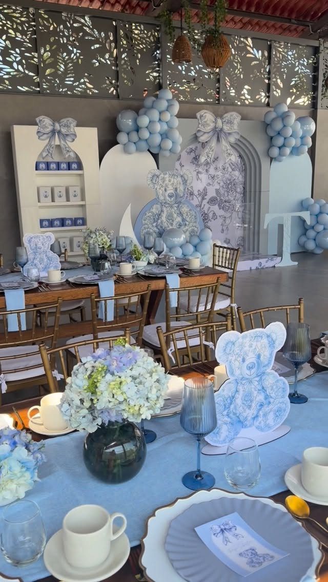 Blue baby shower table setting with teddy bear cutouts and blue balloon decorations.