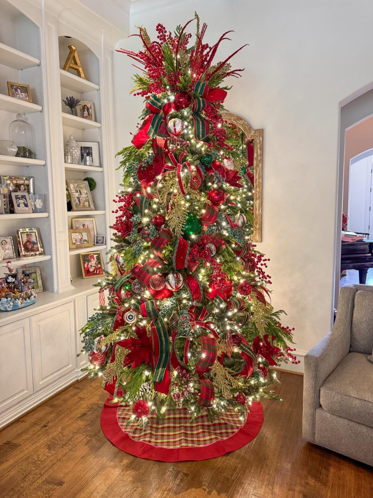 Decorated Christmas tree with red and gold ornaments on a plaid tree skirt.