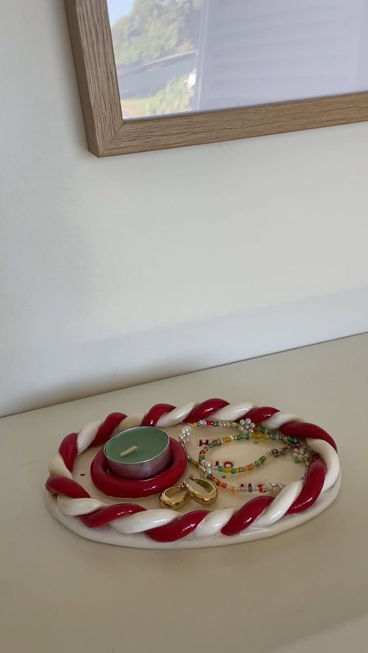 Candy-cane bordered tray holding a green candle, beaded bracelet, and gold earrings.