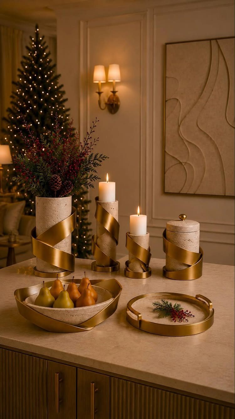 Cream and gold decorative vase with greenery and matching candle holders on a counter.