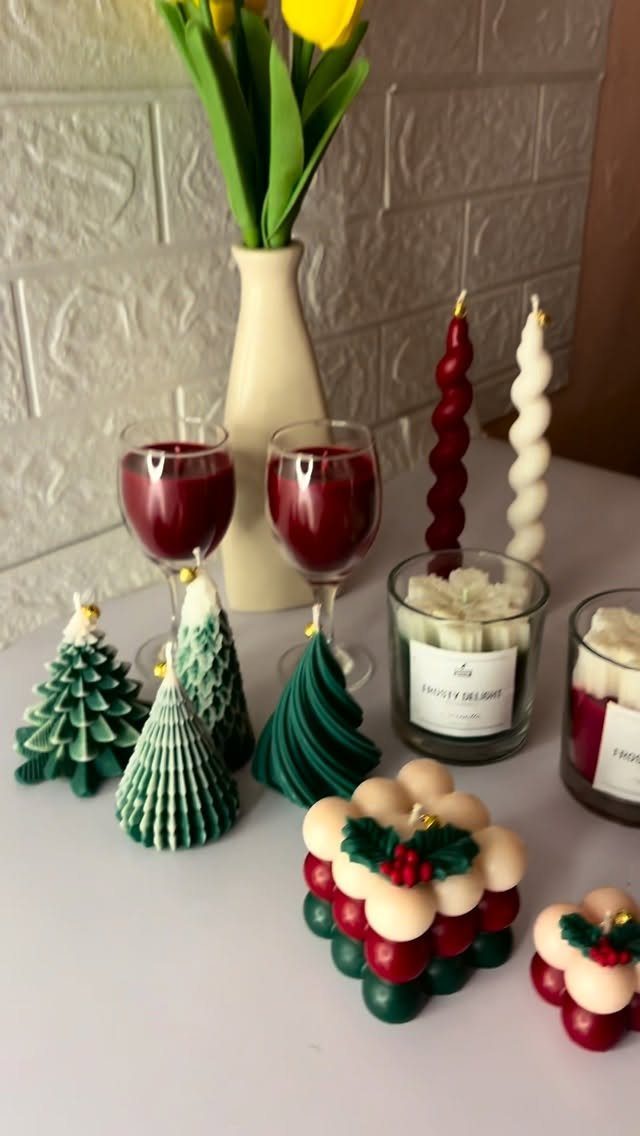 Christmas-themed candles in tree and bubble shapes with red wine and yellow tulips.