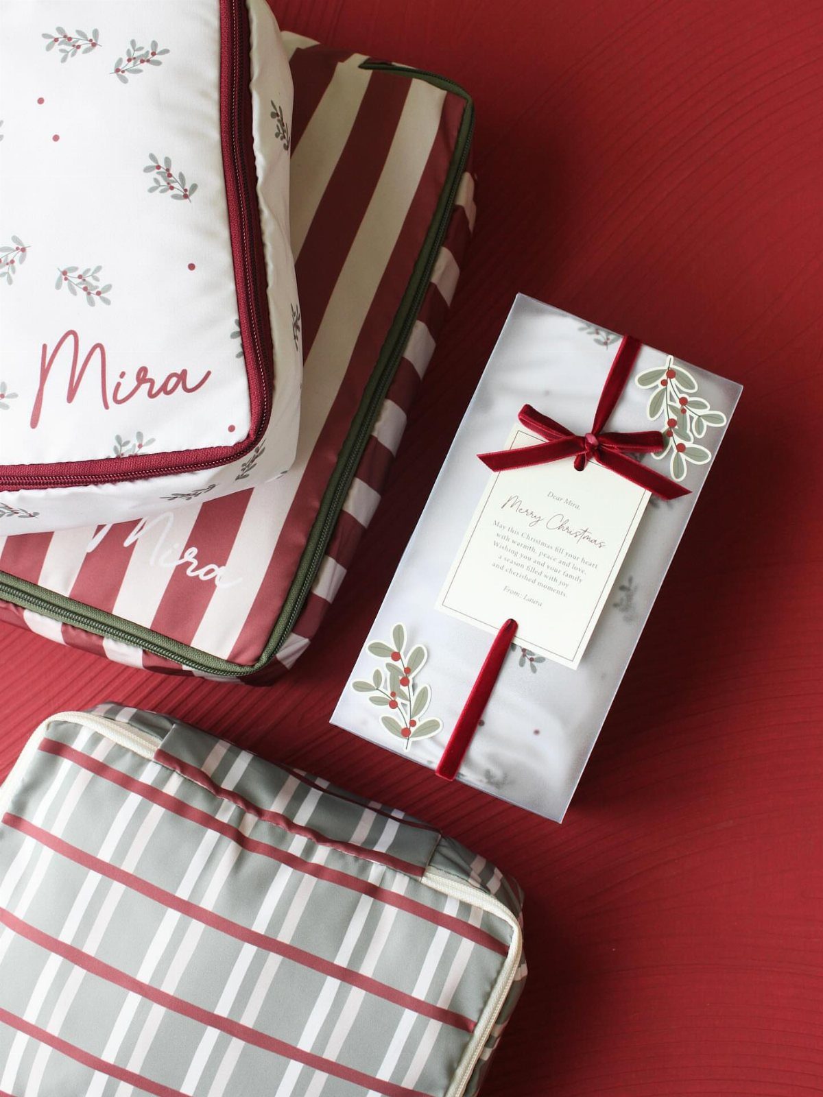 Patterned fabric packing cubes and a wrapped Christmas gift on a red background.
