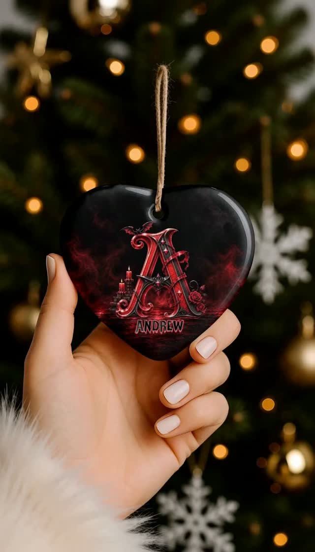 Heart-shaped personalized Christmas ornament with the name Andrew held against a lit tree