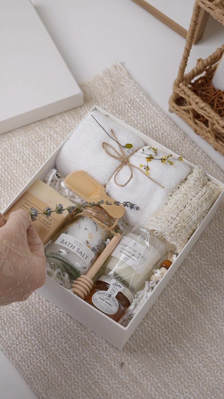 Wellness gift box with bath salts, a candle, honey, and a white towel.