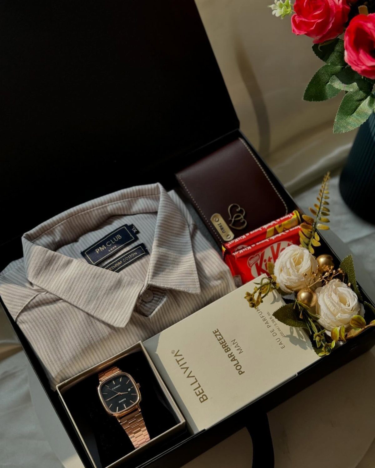 Gift box with a striped shirt, rose gold watch, wallet, and perfume.