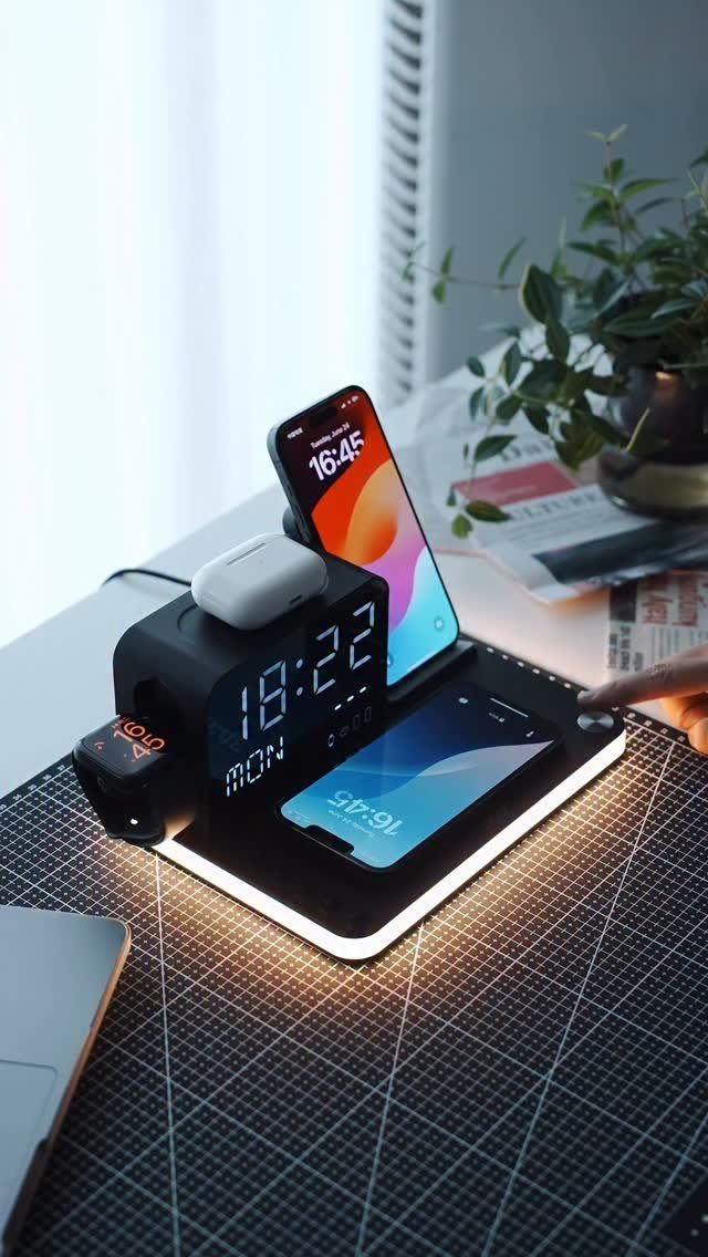 Multi-functional black charging station with digital clock and smartphones on a desk