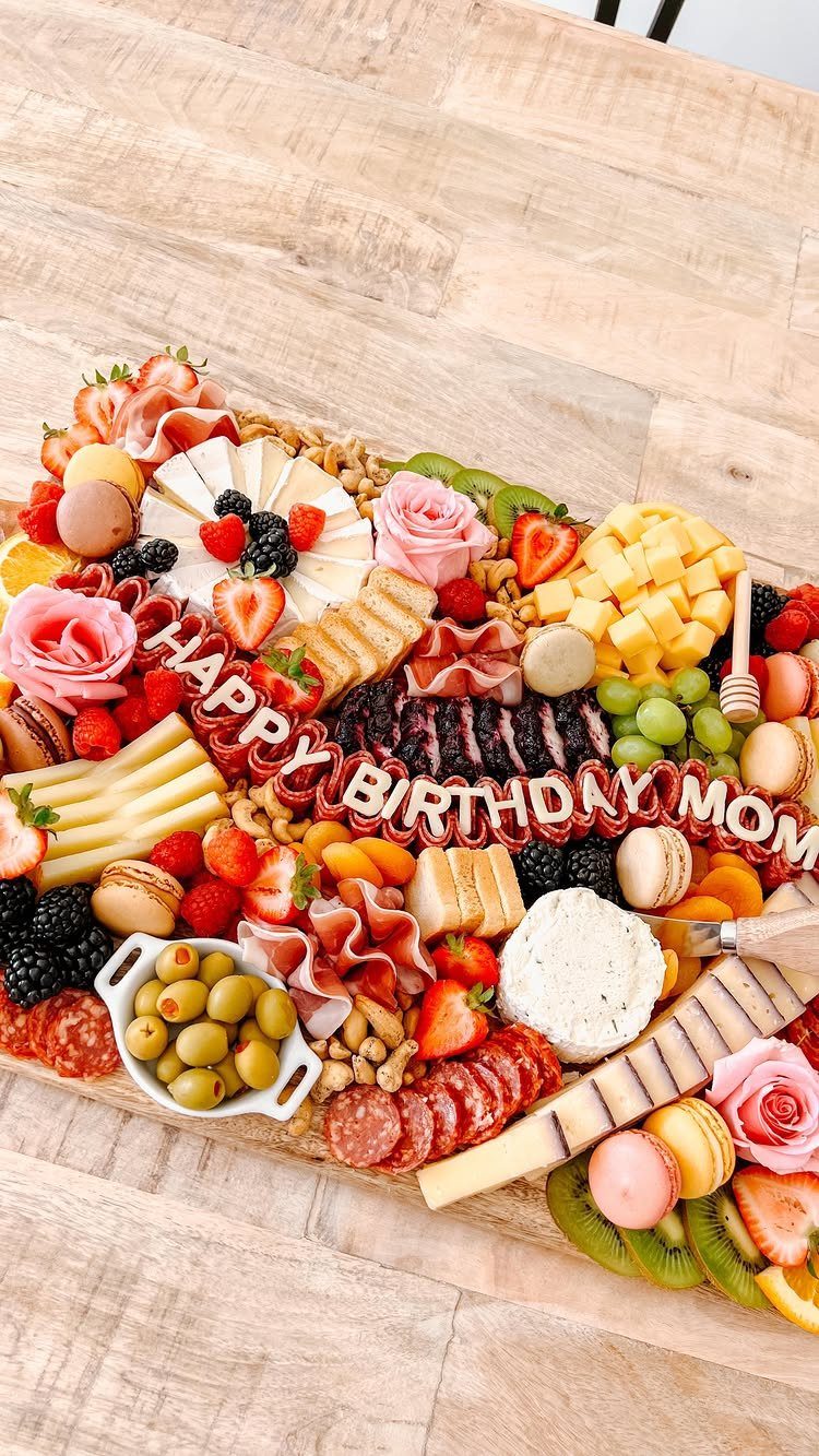 Charcuterie board with meats, cheeses, fruits, and cookies spelling Happy Birthday Mom