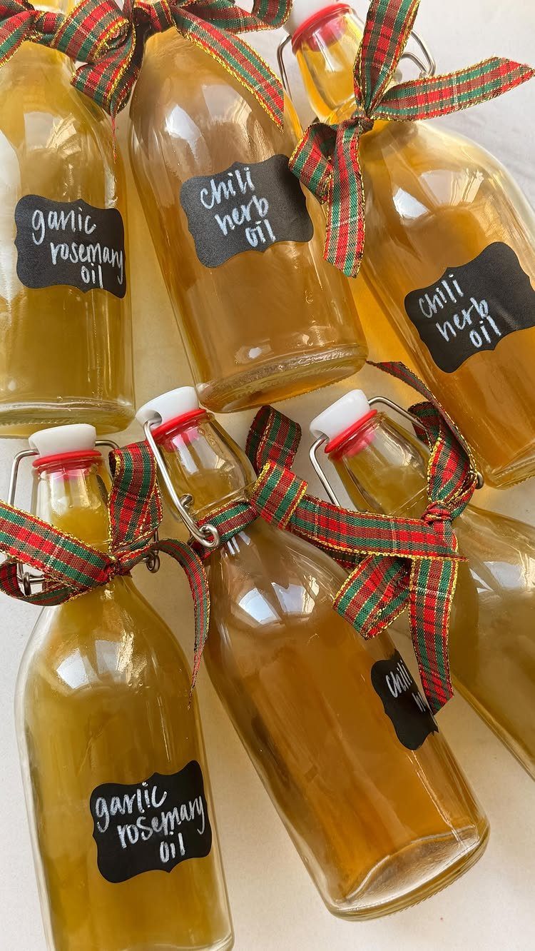 Six bottles of infused olive oil with plaid ribbons and handwritten labels.