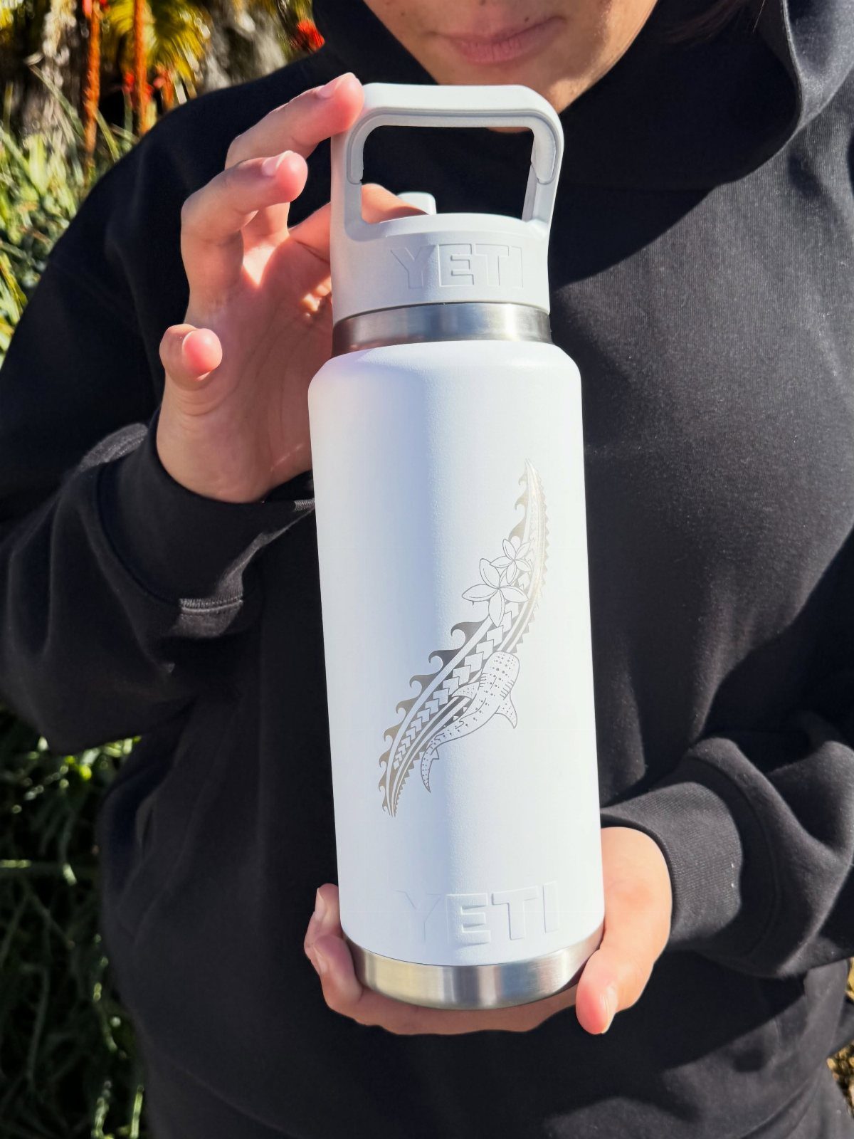 White Yeti insulated water bottle with gold engraving held by a person