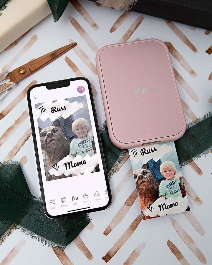 Pink Canon Ivy mini photo printer with a smartphone and a printed photo.