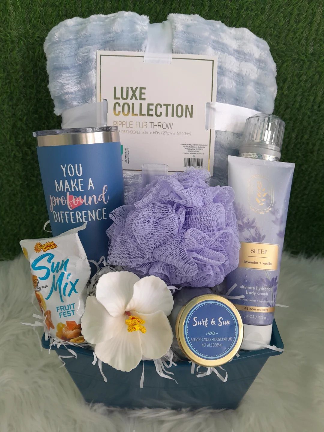 Blue gift basket with a light blue throw blanket, tumbler, and spa items.
