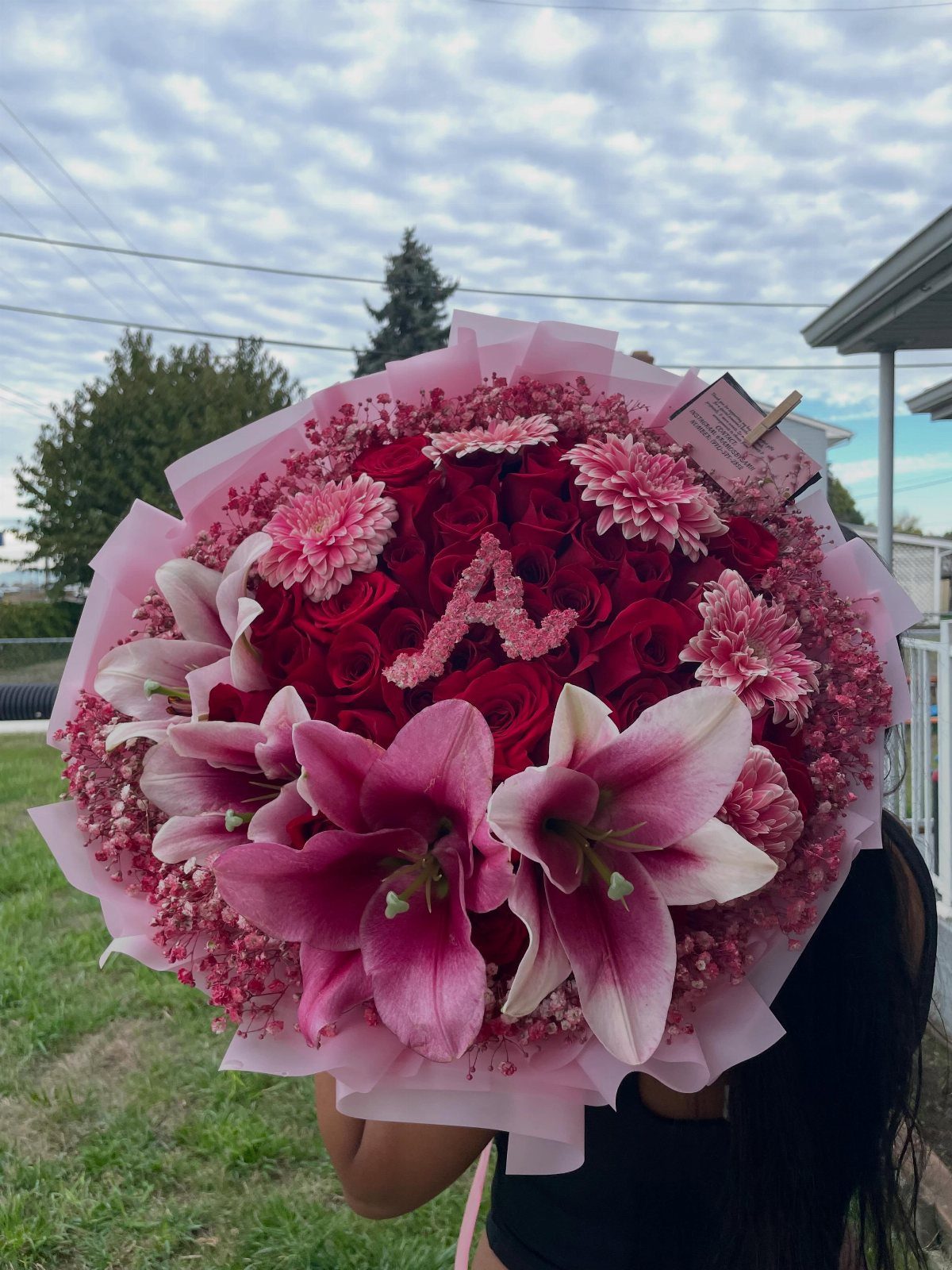 Large round bouquet of red and pink flowers with a floral letter A