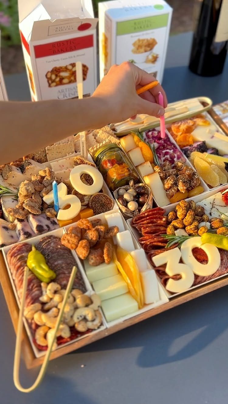Wooden charcuterie board with meats, cheeses, and number 30 birthday candles.