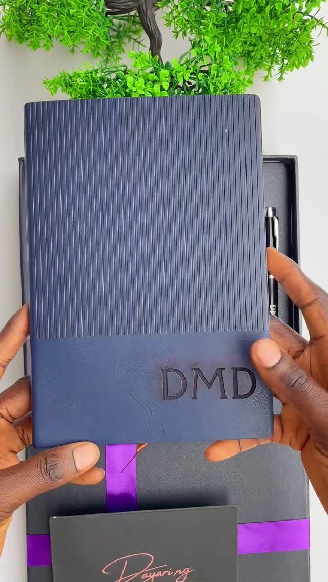 Navy blue textured journal with embossed initials DMD held in a gift set.