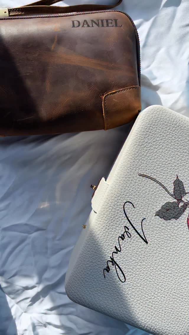 Personalized leather toiletry bags in brown and white on a white fabric background.