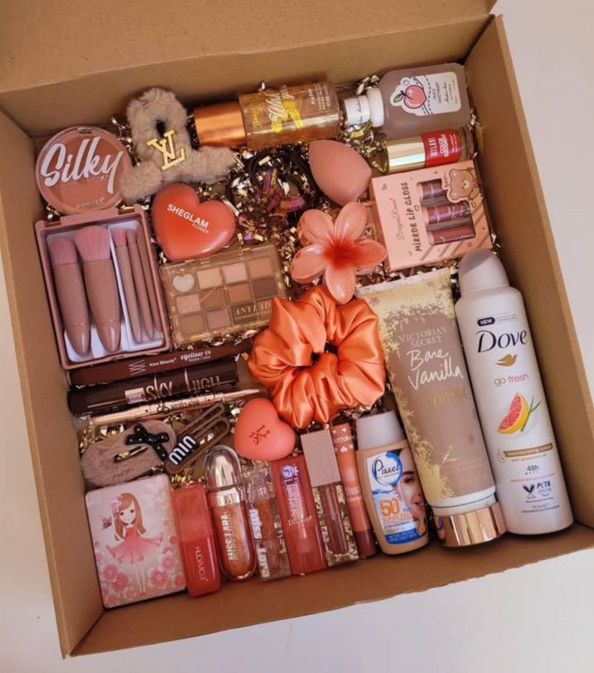Beauty gift box filled with makeup, skincare products, and an orange scrunchie.