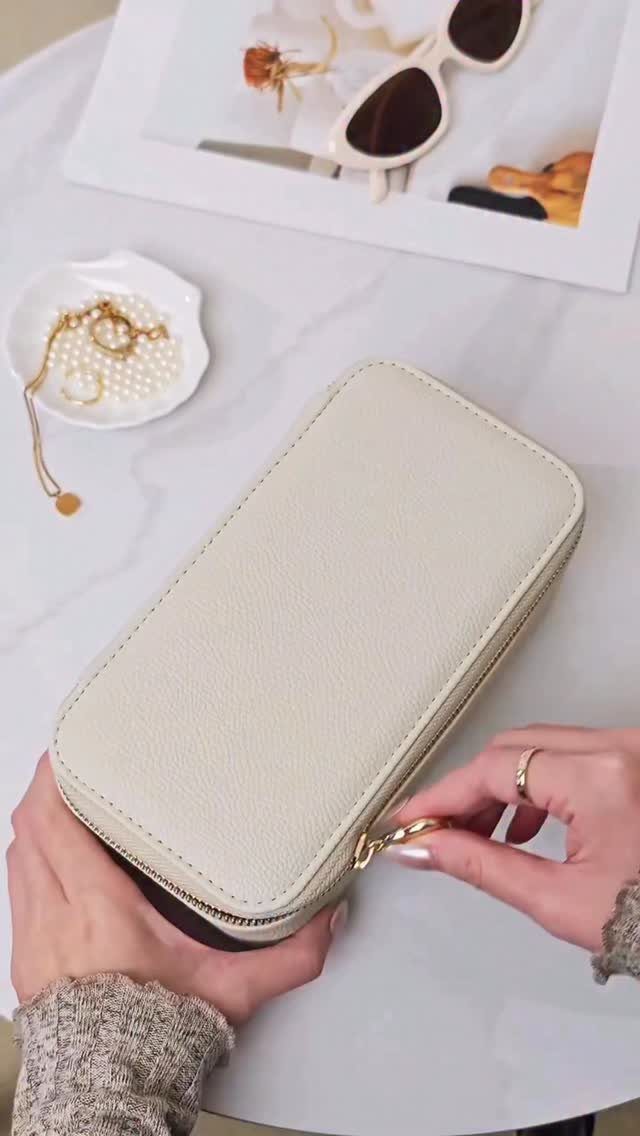 Cream leather zip-around wallet held by hands on a white marble table