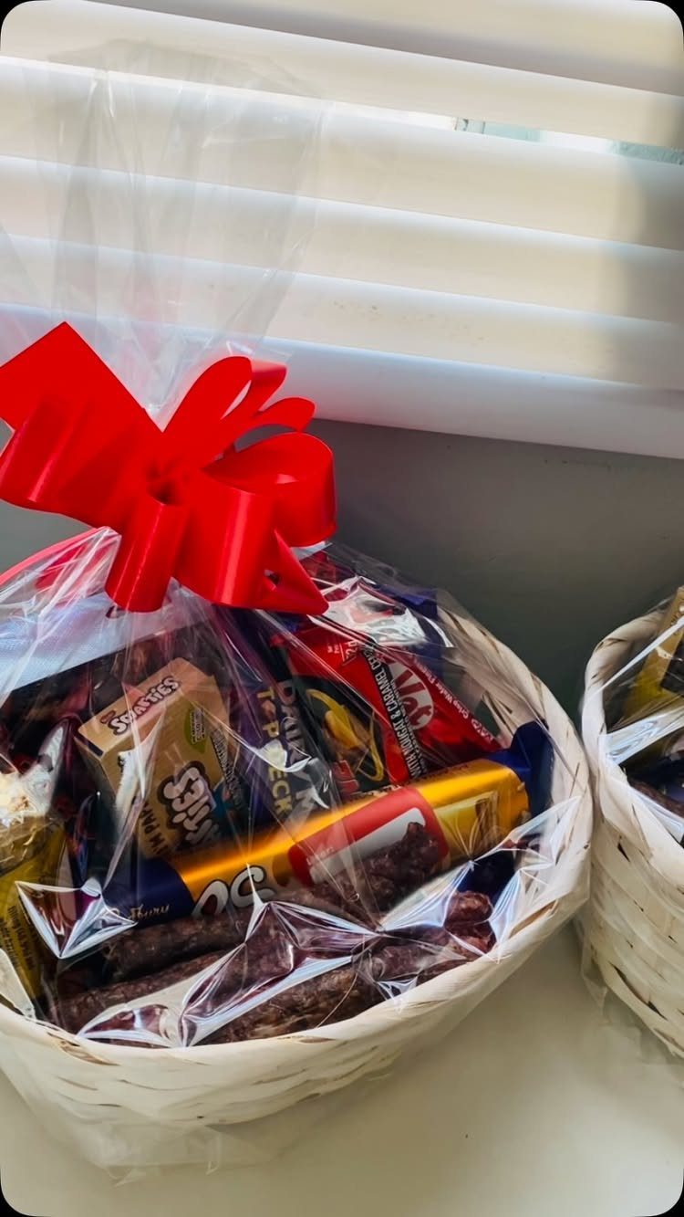 Gift basket filled with assorted chocolates and candies wrapped in cellophane with red bow