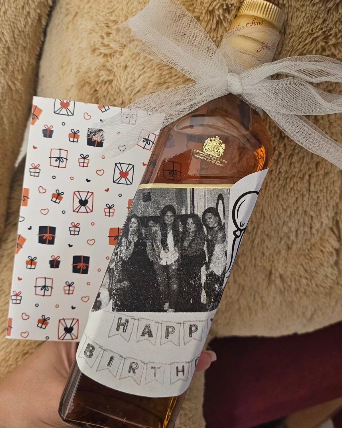 Bottle of liquor with a custom birthday photo label and white ribbon bow.