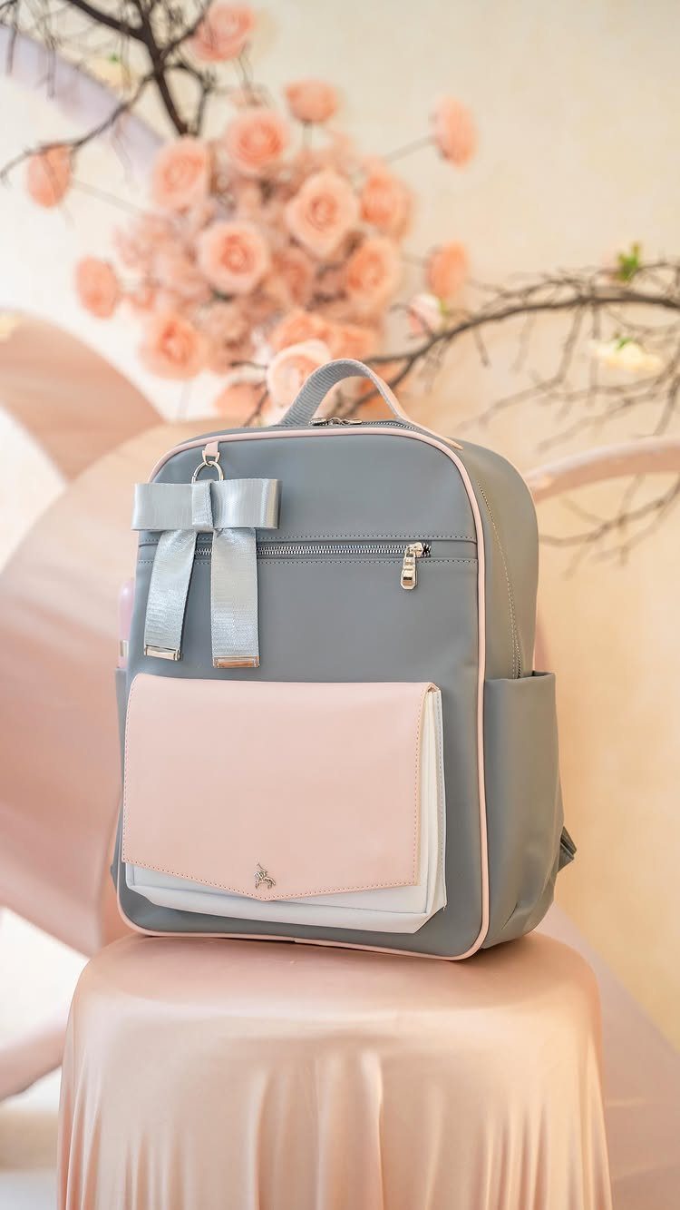 Grey and pink backpack with a silver bow on a pink satin stool