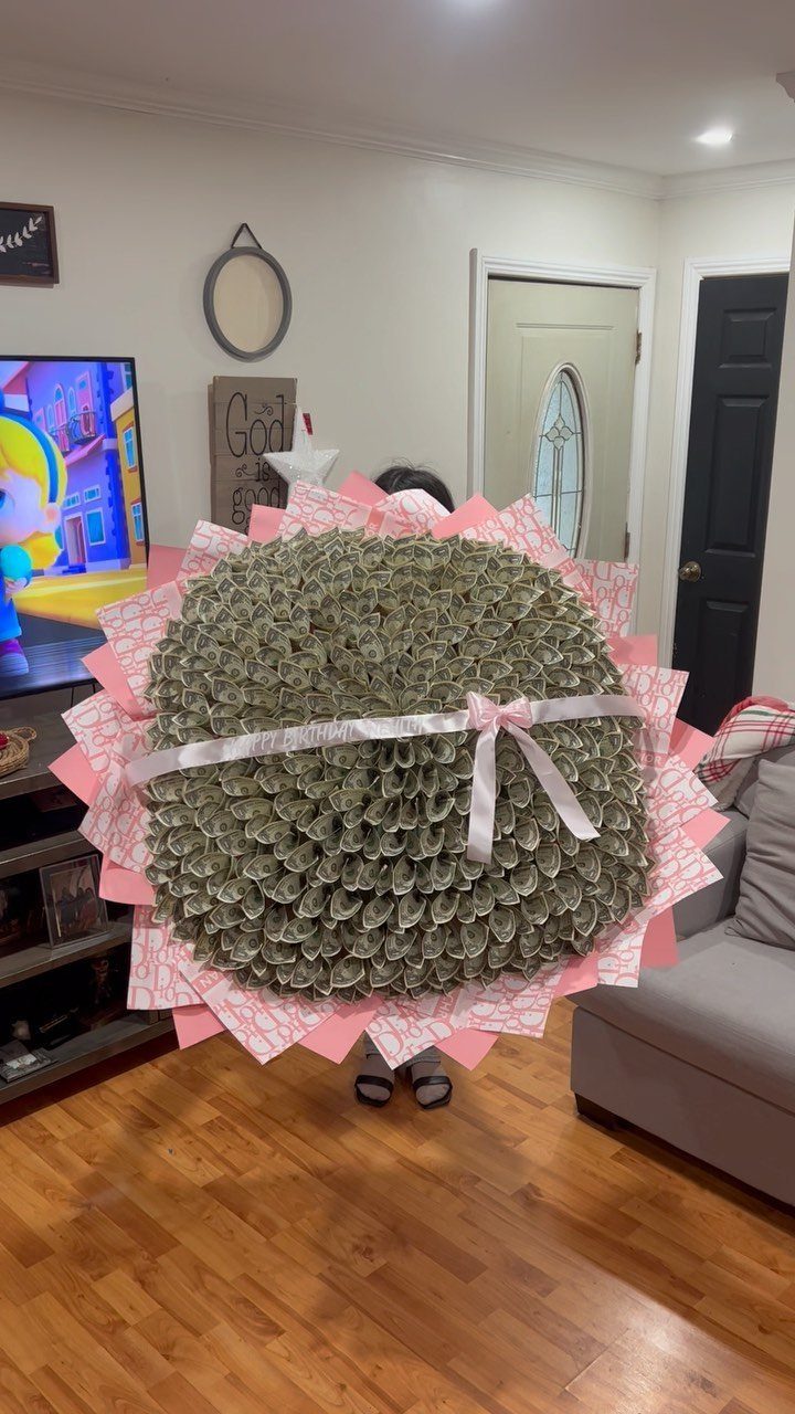 Large money bouquet made of folded dollar bills wrapped in pink paper.