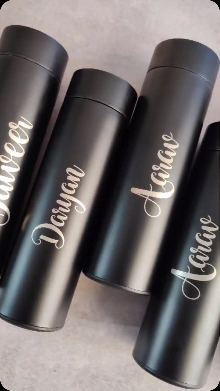 Four matte black insulated water bottles with personalized names in gold cursive script.