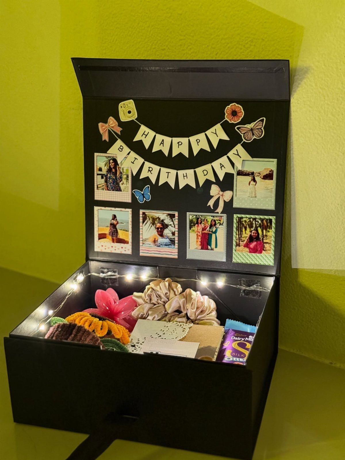Open black birthday gift box with photos, banner, and various small presents inside.